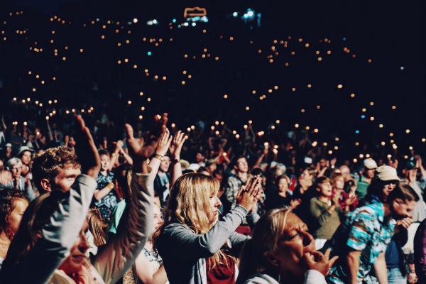 Fans stand with their hands raised at a STAPLES Center concert.