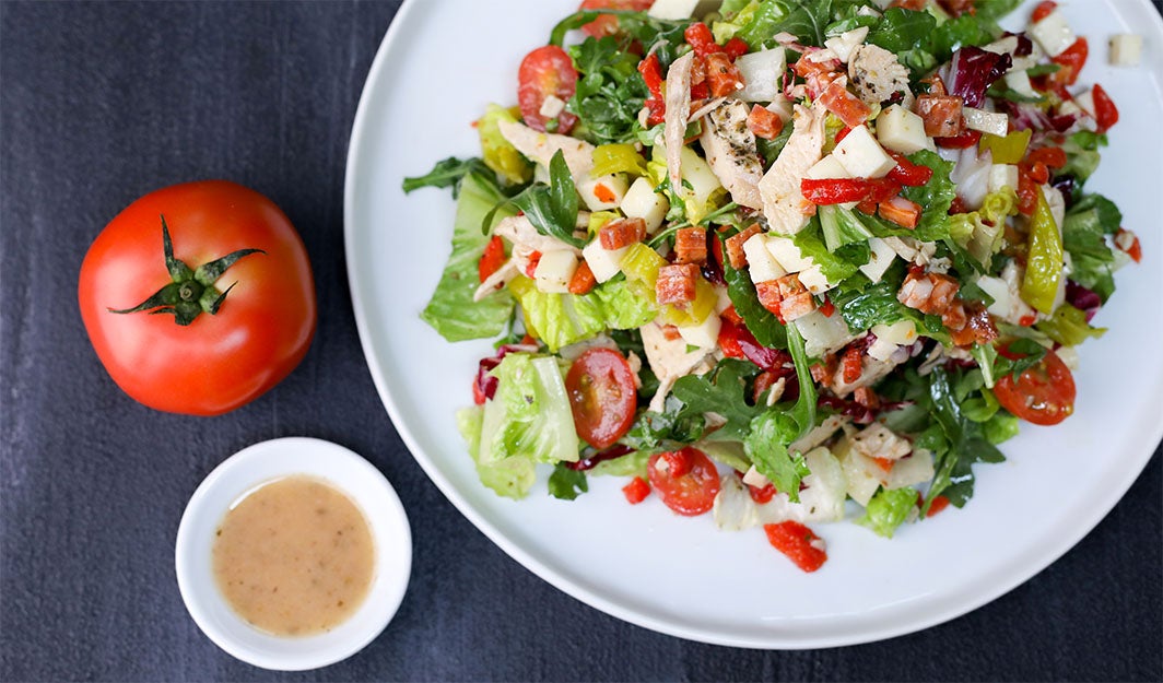 A tomato and chicken salad entree with a side of soup.