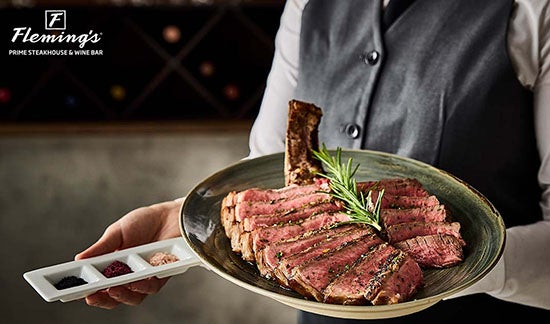 A server with a dish of plated beef at Flemings L.A. LIVE.