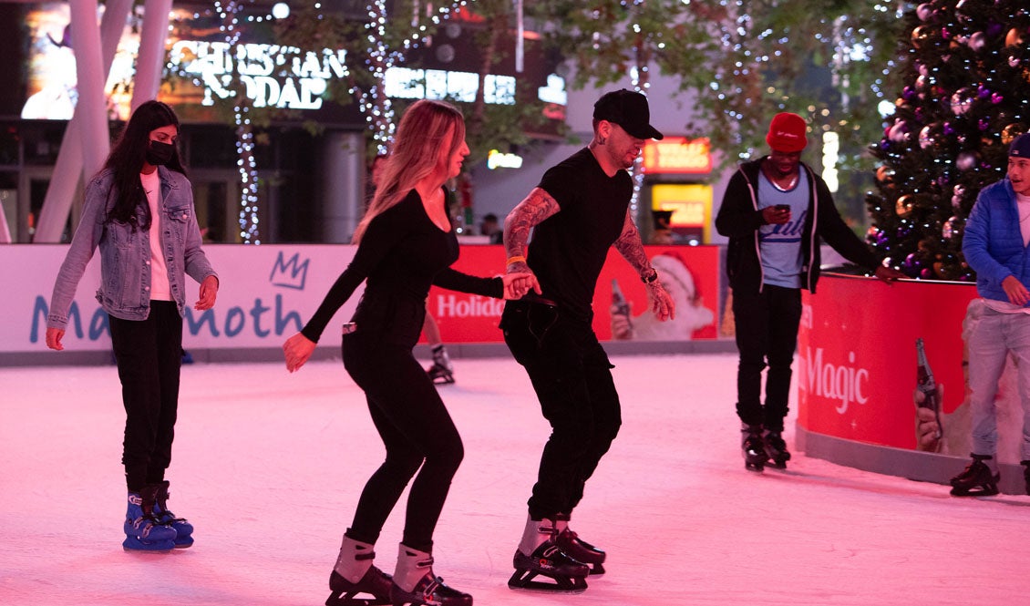 A couple skates with knees bent on the LA Kings Holiday Ice.