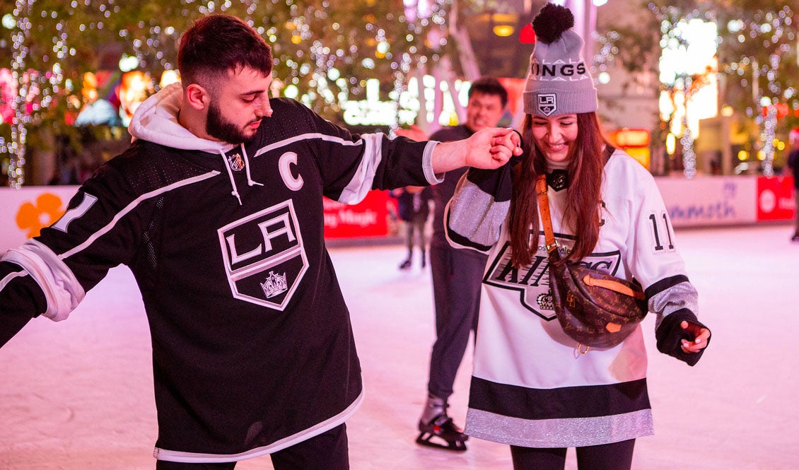 Two people hold hands while standing on the LA Kings holiday Ice.
