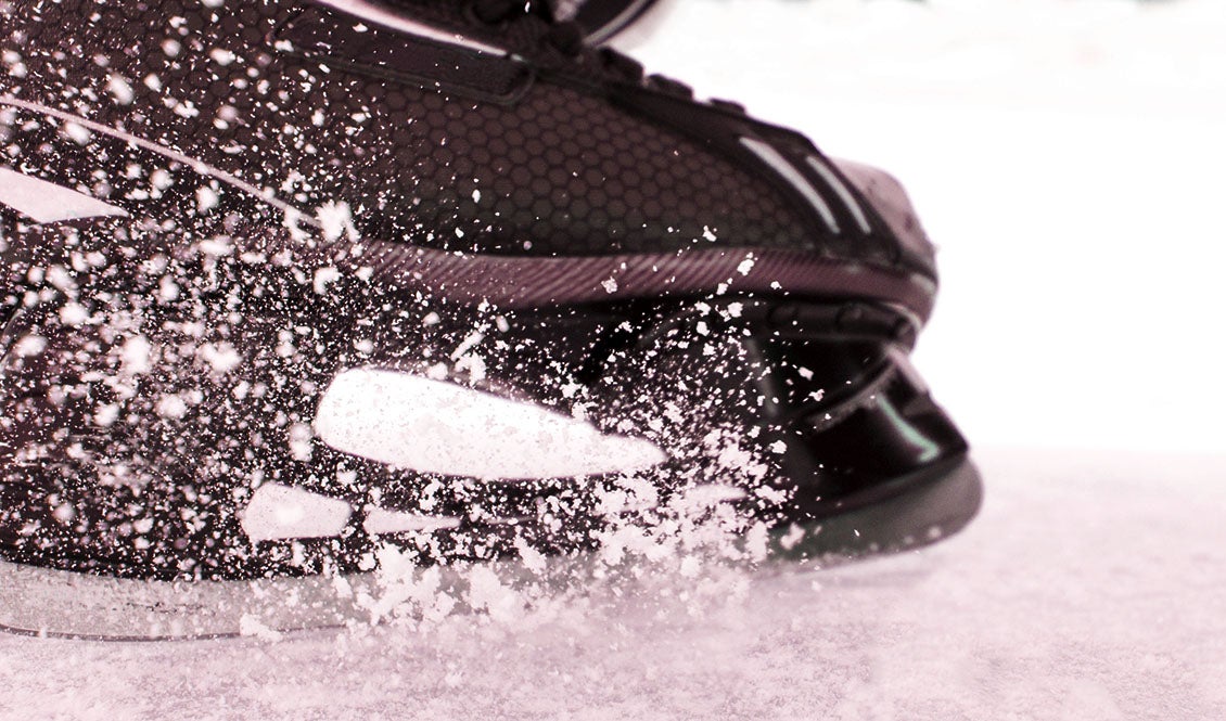 Close up of an ice skate spraying snow in a stop.